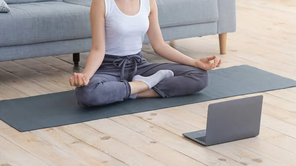 Обрізана жінка медитує перед ноутбуком — стокове фото