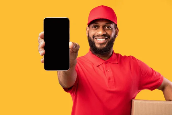 Entrega Hombre Mostrando Smartphone Screen Holding Box sobre fondo amarillo —  Fotos de Stock