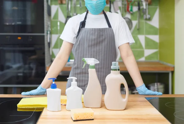 Donna in maschera e guanti che mostra tutti i detergenti ecologici per la disinfezione della cucina — Foto Stock