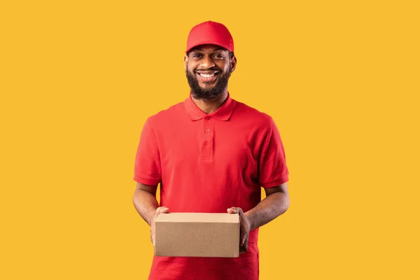 Hombre de mensajero negro en uniforme que sostiene la caja de cartón, Studio Shot — Foto de Stock