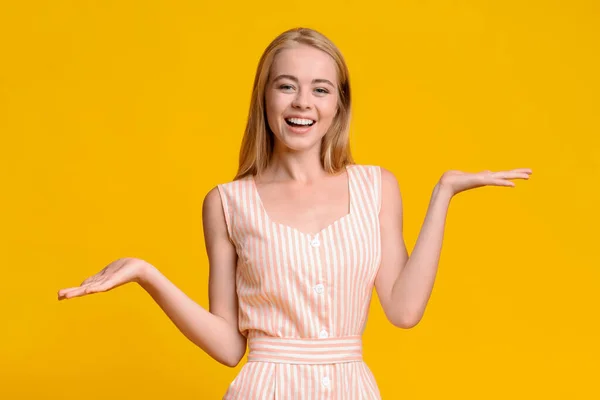Chica alegre en vestido de verano demostrando algo en sus palmas vacías —  Fotos de Stock