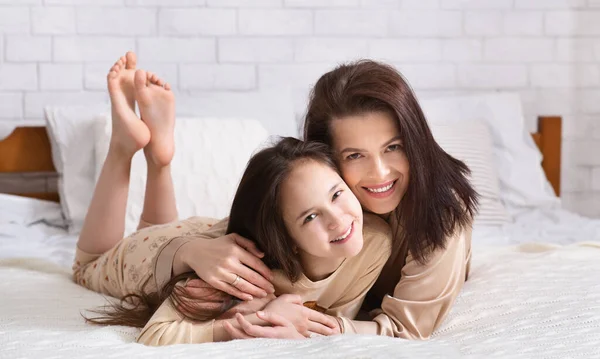 Amor de padre e hijo. Mujer joven abrazando a su hija adolescente en la cama, panorama —  Fotos de Stock