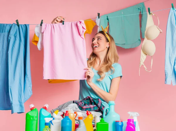 Sorrindo dona de casa pendurado fora limpo tshirt perto de produto de limpeza com espaço vazio — Fotografia de Stock