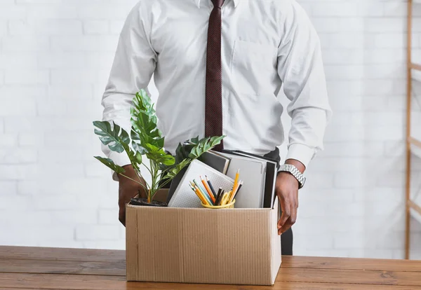 Quitting job concept. Unrecognizable African American employee with box of his belongings at office, closeup