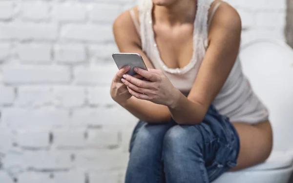 Frau mit Smartphone spielt Handyspiele auf Toilette, abgeschnitten — Stockfoto