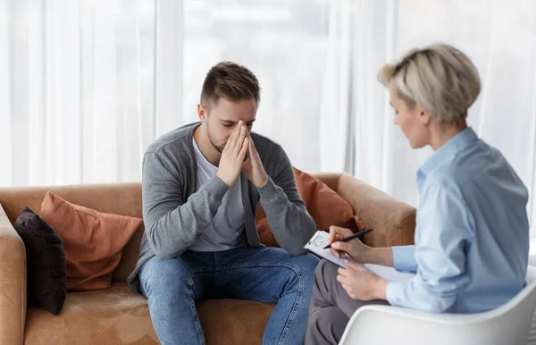 Verzweifelter Mann erzählt vom Leben, während Psychologe Notizen im Haus macht — Stockfoto