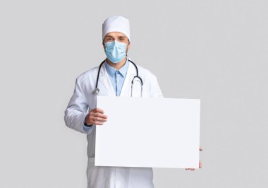 Koruyucu maskeli doktor boş uyarı işareti tutuyor.