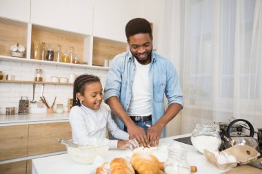 Mutlu Afro-Amerikan ailesi birlikte hamur yoğuruyor.
