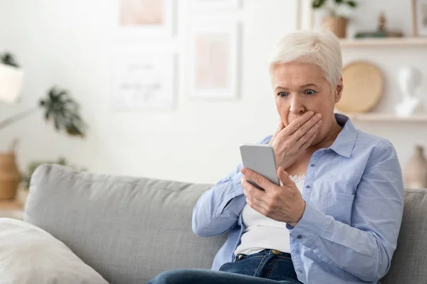 Coronavirus News. Chocado Senior mulher ler informações sobre Smartphone em casa — Fotografia de Stock