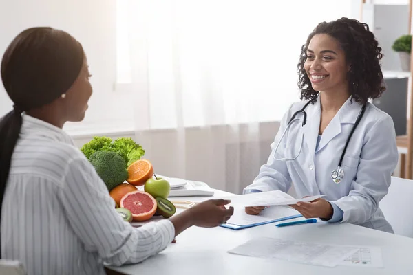 Mulher nutricionista dando paciente folheto informativo, clínica interior — Fotografia de Stock