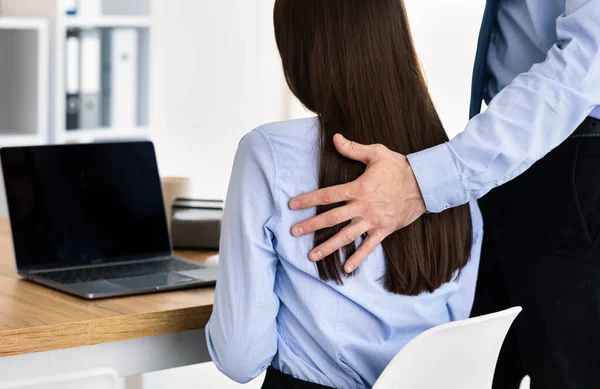 Бізнесмен, що турбує жінку-каучуку, торкається її плеча в офісі, задній план — стокове фото
