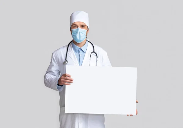 Doctor en máscara protectora sosteniendo señal de advertencia en blanco — Foto de Stock