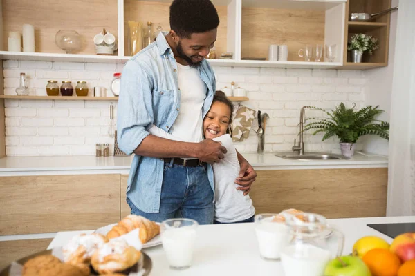 Vděčná holčička objímající svého otce s láskou v kuchyni — Stock fotografie