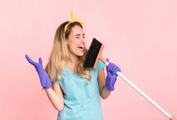 Un concepto de limpieza divertido. Ama de casa en guantes de goma cantando en escoba — Foto de Stock