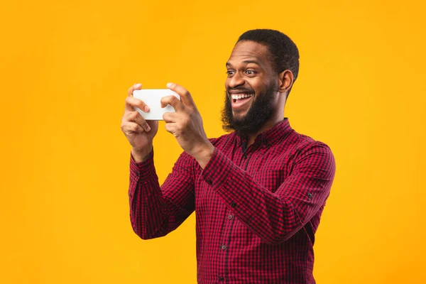 Ενθουσιασμένος άνθρωπος afro χρησιμοποιώντας το κινητό τηλέφωνο σε πορτοκαλί φόντο — Φωτογραφία Αρχείου