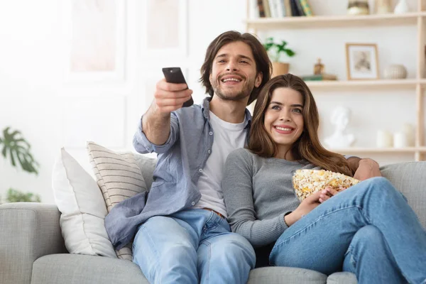 Encantador casal assistindo TV em casa e comer pipocas — Fotografia de Stock