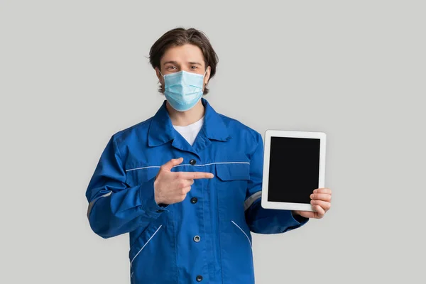 Rekrutacja pracowników budowlanych podczas koronawirusu. Laborer w masce wskazując na tablecie cyfrowym — Zdjęcie stockowe