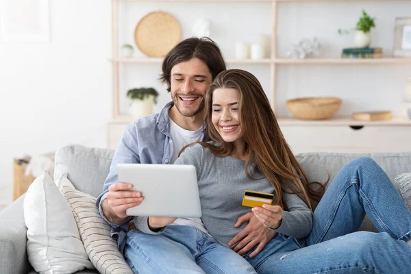 Casal feliz compra on-line, segurando cartão de crédito e tablet digital — Fotografia de Stock