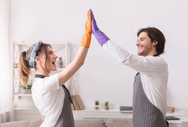 Genç eşler birlikte temizlik yaptıktan sonra birbirlerine beşlik çakıyorlar.