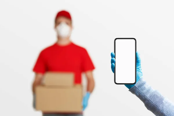 Delivery of packages on time concept, and hand with smartphone with blank screen