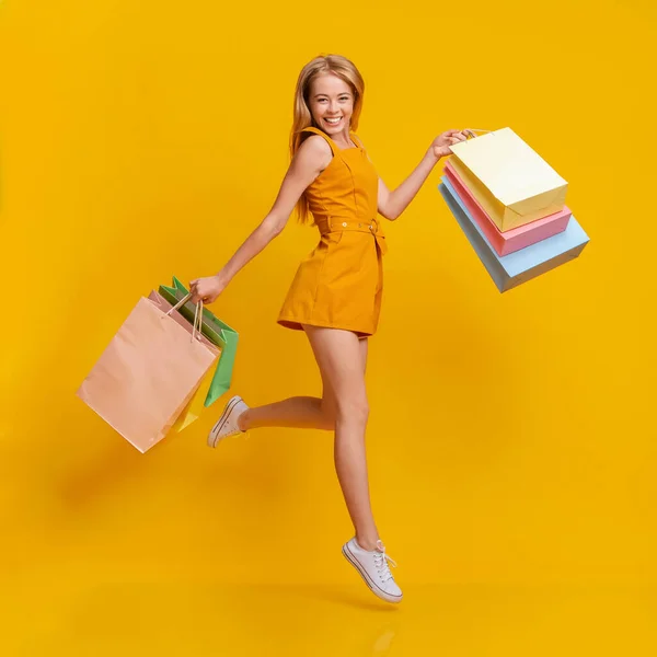 Saisonverkäufe. Schöne Shopaholic junge Mädchen springen mit Einkaufstaschen in den Händen — Stockfoto
