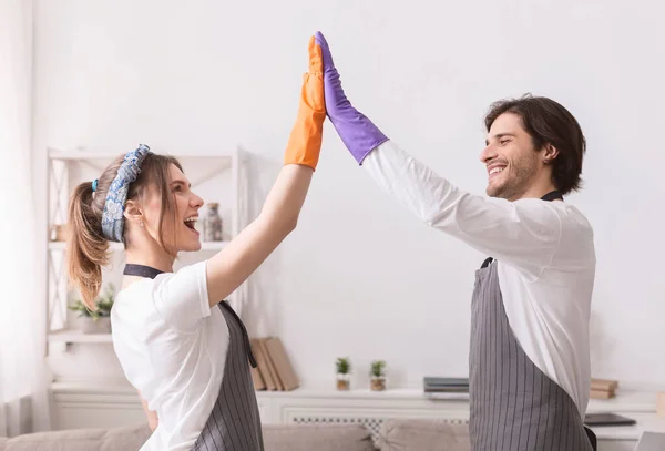Jovens cônjuges dando alta cinco uns aos outros depois de limpar plana juntos — Fotografia de Stock