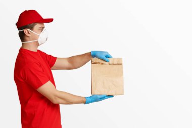 Hassas bir kargo. Maskeli ve eldivenli kurye paketi dikkatlice tutar.