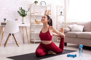 Yogi kadın oturma odasında günlük antrenman yapıyor.