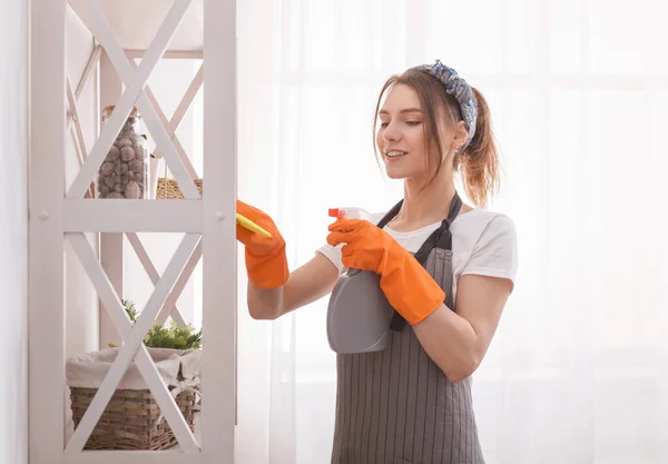 Professionelles Hausmädchen. Junge Frau in Schürze putzt Staub aus Regal — Stockfoto