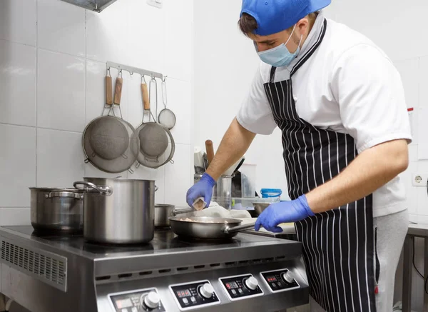 Man in protective mask and gloves frying tasty food — Stock Photo, Image