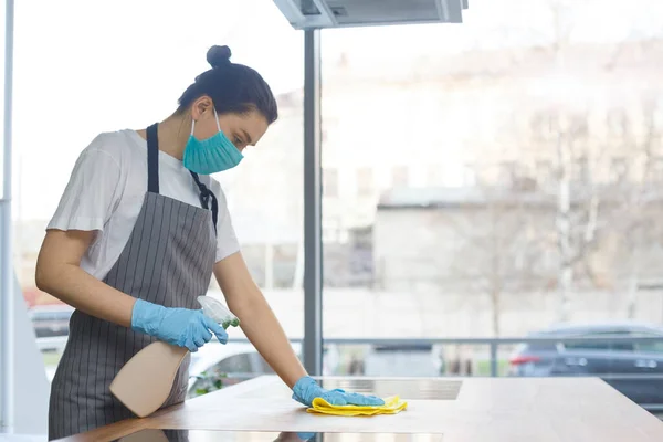 Kobieta dezynfekująca powierzchnię kuchni od infekcji detergentem natryskowym — Zdjęcie stockowe
