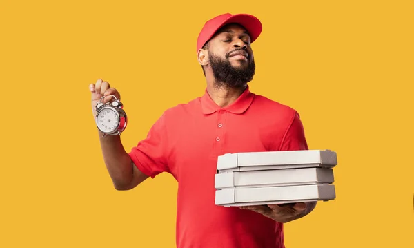 Courier entregando caixas de armazenamento de pizza e relógio em fundo amarelo — Fotografia de Stock