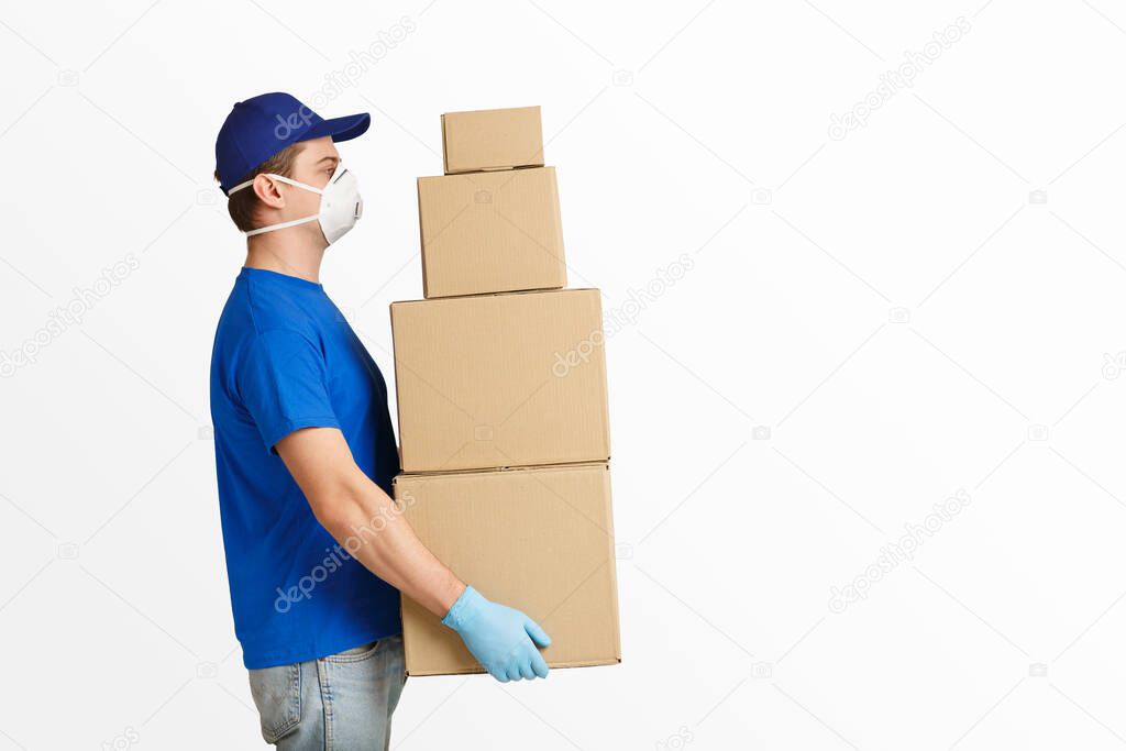 Parcels delivery during quarantine concept. Courier in protective mask holds a lot of cardboard boxes