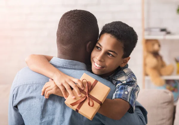 Gelukkig zwart jongen knuffelen vader en geven hem Geschenk Box — Stockfoto