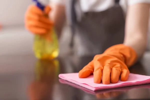 Donna irriconoscibile che pulisce la polvere dal tavolo con tappetino e detergente spray — Foto Stock