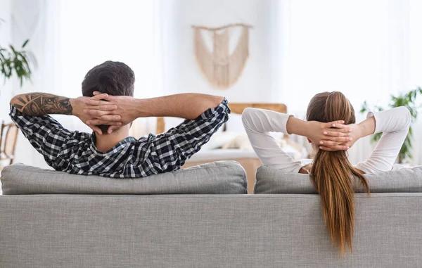 Repos commun. Guy et fille se détendre sur le canapé avec les mains serrées derrière la tête . — Photo