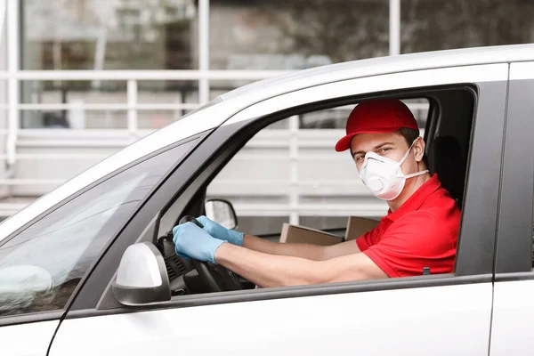 Tukang antar berseragam merah dengan masker medis dan mobil penggerak sarung tangan. — Stok Foto