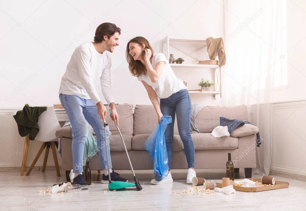 Laughing Young Couple Cleaning Mess In Their Flat After Party