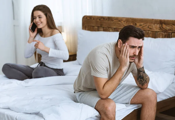Tired of phone calls. Girl talking on smartphone, guy holds to head — Stock Photo, Image