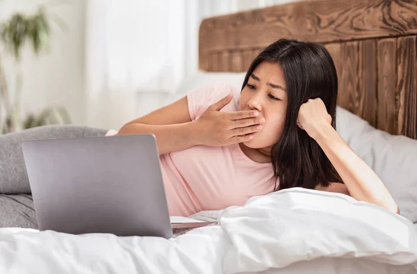 Entediado ásia menina usando laptop deitado no cama no casa — Fotografia de Stock