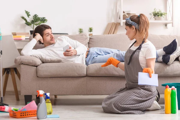 Frustrated Woman Cleaning Flat And Arguing With Lazy Husband Lying On Couch — Stock Photo, Image