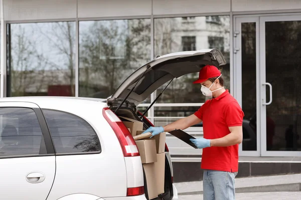 Karantæne og levering i hjemmet koncept. Courier åben bagagerum af bil, tager ud parcel - Stock-foto