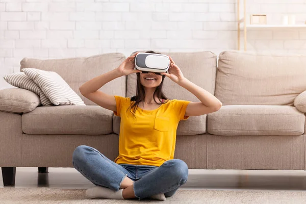 Chica milenaria en auriculares de realidad virtual explorando el ciberespacio, jugando videojuego interactivo en casa — Foto de Stock