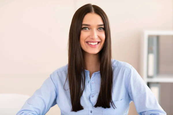 Veselá kancelářská dívka usmívající se na kameru stojící na pracovišti — Stock fotografie
