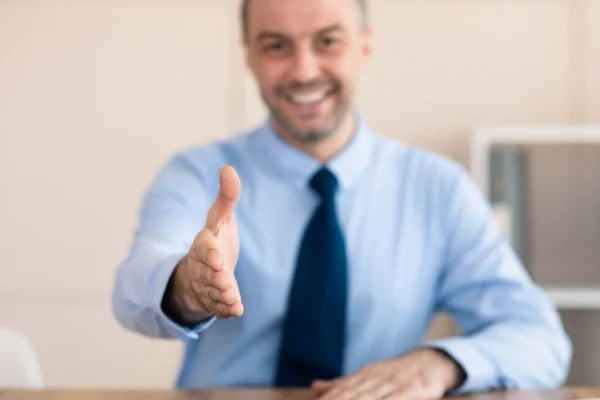Empresario estirando la mano para el saludo del apretón de manos sentado en la oficina moderna —  Fotos de Stock