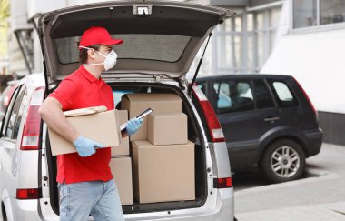 Covid-19 salgını sırasında kargo paketleri. Kurye kutu ve tablet tutar, istemciye paket verecek