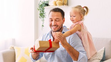 Heyecanlı kız, hediyesini babasıyla birlikte tutuyor.