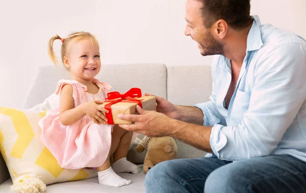 Garota excitada segurando seu presente sentado com o pai — Fotografia de Stock