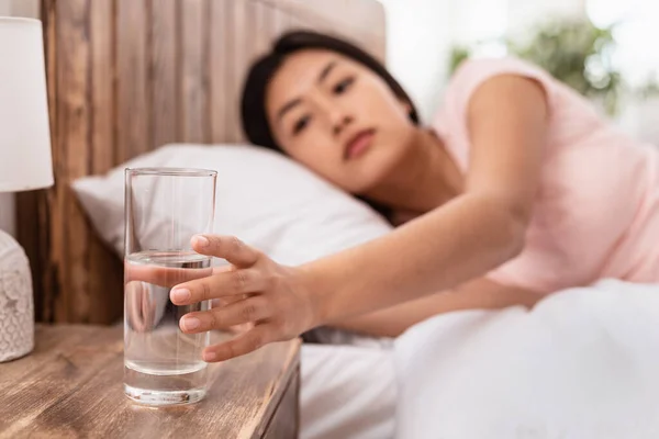 Asiática señora bebiendo agua acostado en cama en casa — Foto de Stock