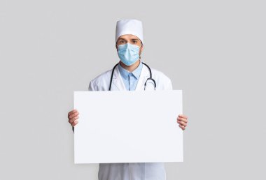 Boş beyaz tabelası olan koruyucu giyimli bir doktor.